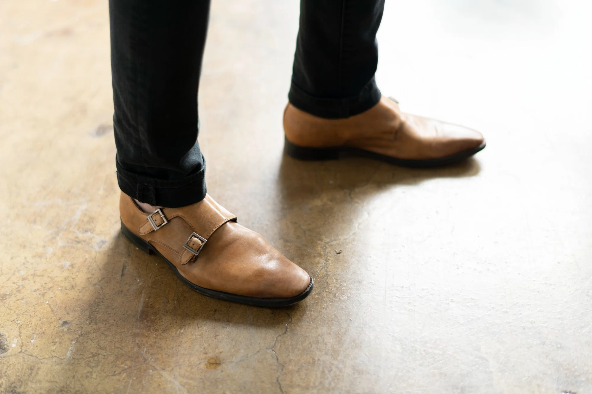 Young man sits on the floor and shows his shoes to the camera