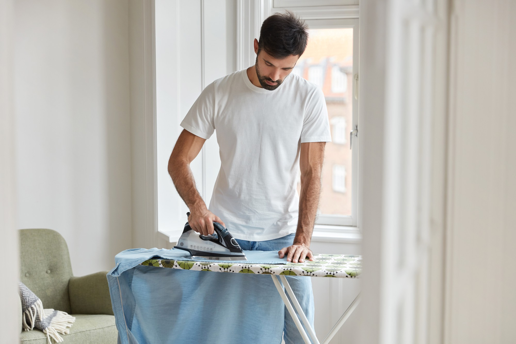 Ein Mann bügelt sein T-Shirt auf einem Bügelbrett